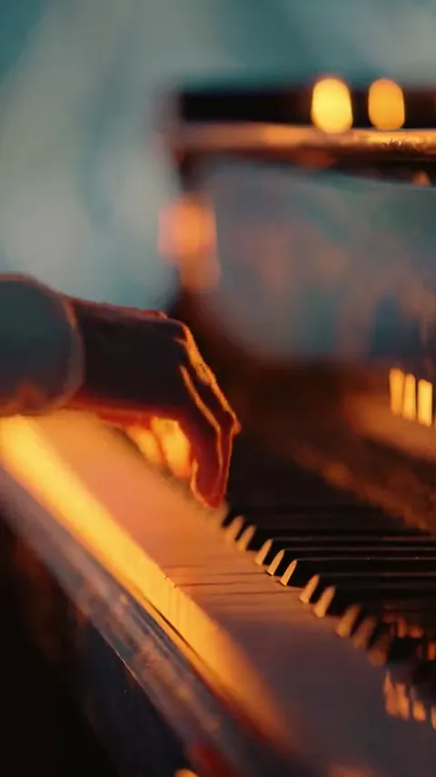 Hands on piano keys lit by candles