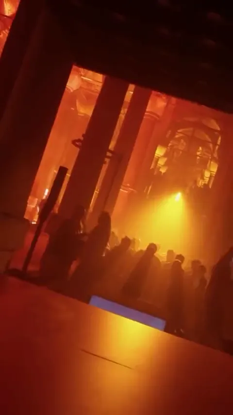 Crowd in an amber-lit hall at an art event
