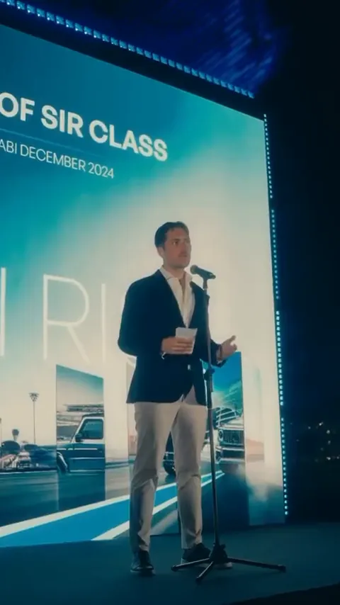 Speaker on stage in front of a large screen