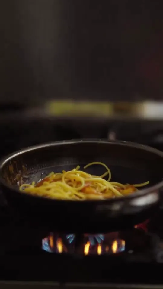Noodles in a pan over an open flame